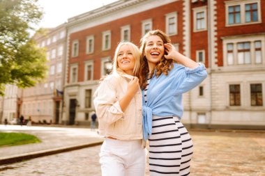 İki arkadaş, tarihi bir şehrin kaldırım taşı sokağında neşeli bir şekilde poz vererek güneşli havalarda dışarıda vakit geçiriyorlar.