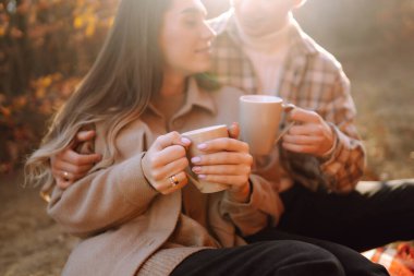 Günbatımında yapraklarla çevrili, sonbahar ormanlarında romantik bir yürüyüş yapan genç bir çift.