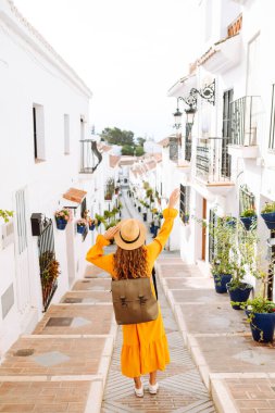 Güzel gezgin kadın eski kasabada güzel bir yürüyüşün tadını çıkarıyor. O güzel parlak bir elbise ve bir sırt çantası giyiyor. Yaşam tarzı kavramı, tatil, moda, seyahat.