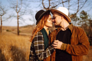 Çiftler, sıcak bir sonbahar öğleden sonrasında dağlarda bir tarlada otururken altın güneş ışığında kucaklaşırlar. Romantik randevu doğanın romantizm ilişkileri kavramında.