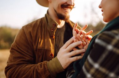 Çiftler, sıcak bir sonbahar öğleden sonrasında dağlarda bir tarlada otururken altın güneş ışığında kucaklaşırlar. Romantik randevu doğanın romantizm ilişkileri kavramında.