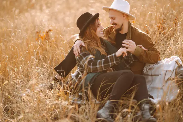 Çiftler, sıcak bir sonbahar öğleden sonrasında dağlarda bir tarlada otururken altın güneş ışığında kucaklaşırlar. Romantik randevu doğanın romantizm ilişkileri kavramında.