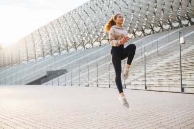 Spor yapan ve güzel bir yaz akşamının tadını çıkaran güzel bir kadının portresi. Atletizm kıyafetleri içinde enerjik ve antrenman için hazır görünüyor. Sağlıklı yaşam tarzı.