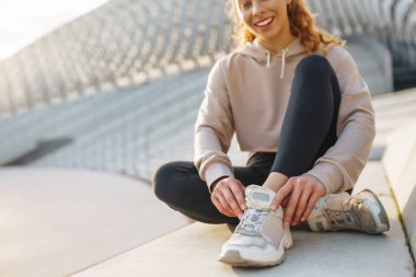 Spor yapan ve güzel bir yaz akşamının tadını çıkaran güzel bir kadının portresi. Atletizm kıyafetleri içinde enerjik ve antrenman için hazır görünüyor. Sağlıklı yaşam tarzı.