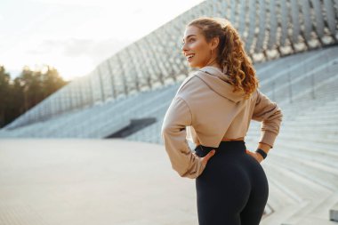 Spor yapan ve güzel bir yaz akşamının tadını çıkaran güzel bir kadının portresi. Atletizm kıyafetleri içinde enerjik ve antrenman için hazır görünüyor. Sağlıklı yaşam tarzı.