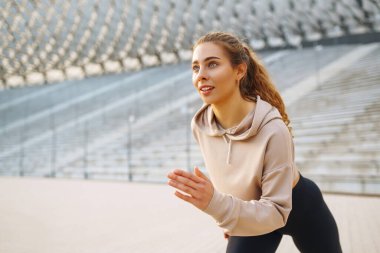 Spor yapan ve güzel bir yaz akşamının tadını çıkaran güzel bir kadının portresi. Atletizm kıyafetleri içinde enerjik ve antrenman için hazır görünüyor. Sağlıklı yaşam tarzı.