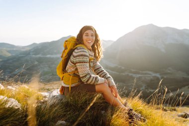 Neşeli bir yürüyüşçü dingin eteklerde güneşli bir öğleden sonra bir dağ zirvesinden nefes kesici manzaranın tadını çıkarır. Doğa, aktif yaşam, seyahat.