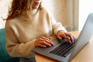 Öğleden sonra sıcak ve davetkar bir atmosferle çevrili bir kafede dizüstü bilgisayarda yazı yazan biri. Teknoloji, internet, serbest çalışan, çevrimiçi eğitim, alışveriş.