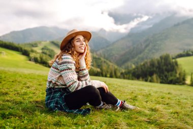 Genç gezgin kadın, gündüz vakti şapka takıp manzaranın tadını çıkarıyordu. Seyahat, doğa konsepti.
