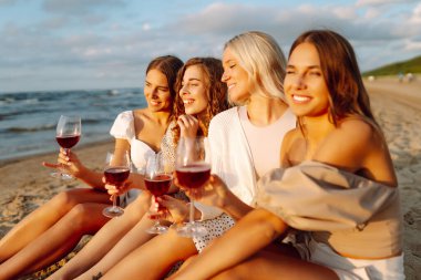 Dört kadın sahilde birlikte oturur, ellerinde kırmızı şarap kadehleriyle, güzel bir günde sıcak güneşin ve manzaranın tadını çıkarırlar. Kızlar partisi..
