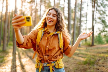 Doğadaki selfie. Güneşli bir ormanda yürürken fotoğrafını çeken güzel bir kadın.. 