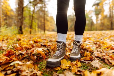 Canlı bir orman ortamındaki renkli yapraklarla çevrili sağlam çizmelerle sonbahar patikalarını keşfediyorum. Ormanda güzel bir sonbahar gününün tadını çıkarıyorum..