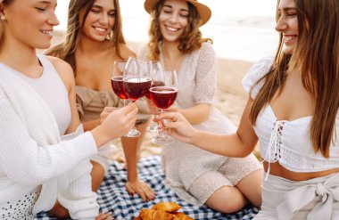 Dört arkadaş plajda kutlama yapıyor, kırmızı şarap kadehlerini kaldırıyorlar. Güneş arka planda batar, sıcak ve neşeli bir atmosfer yaratır. Kızlar partisi..