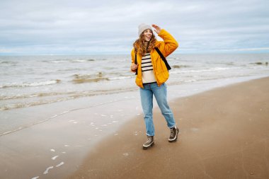 Seyahat eden kadın kıyıda yürüyor, temiz deniz havasının tadını çıkarıyor. Sakinlik ve sükunet. Seyahat, turizm konsepti.