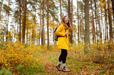 Mutlu kadın ormanda eğleniyor ve sonbahar havasının tadını çıkarıyor. Sakinlik ve sükunet. Seyahat, turizm konsepti.