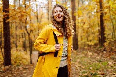 Mutlu kadın ormanda eğleniyor ve sonbahar havasının tadını çıkarıyor. Sakinlik ve sükunet. Seyahat, turizm konsepti.