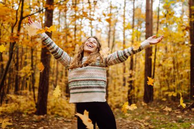 Mutlu kadın ormanda eğleniyor ve sonbahar havasının tadını çıkarıyor. Sakinlik ve sükunet. Seyahat, turizm konsepti.