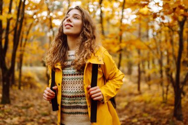 Mutlu kadın ormanda eğleniyor ve sonbahar havasının tadını çıkarıyor. Sakinlik ve sükunet. Seyahat, turizm konsepti.