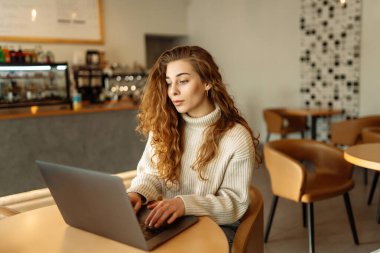 Kafede dizüstü bilgisayarla çalışan genç bir kadın. Eğitim ve iş kavramı. İnternetten alışveriş.