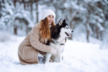 Genç bir kadın kış ormanında köpeğiyle yürür. İri köpek. Evcil hayvan sahibi köpeğini dışarıda gezdirmekten hoşlanır. Dostluk konsepti, evcil hayvanlar.