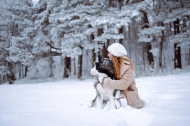 Genç bir kadın kış ormanında köpeğiyle yürür. İri köpek. Evcil hayvan sahibi köpeğini dışarıda gezdirmekten hoşlanır. Dostluk konsepti, evcil hayvanlar.