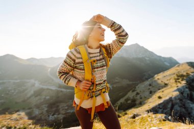 Kadın turist, sırt çantasıyla dağlarda durmuş manzarayı seyrediyor. Doğa, aktif yaşam, seyahat.