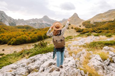 Dişi turist malzeme dolu sırt çantasıyla kayalık arazide dikkatle dolaştı. Sonbahar manzarası. Seyahat, doğa konsepti.