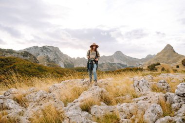 Dişi turist malzeme dolu sırt çantasıyla kayalık arazide dikkatle dolaştı. Sonbahar manzarası. Seyahat, doğa konsepti.