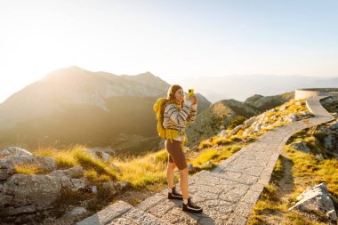 Anıları yakalamak. Genç bir kadın telefon için Negosh Anıt Mezarı 'na gitti. Turizm, doğa, blog konsepti.