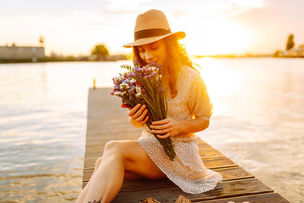 Молодая женщина стояла на мосту, глядя на реку внизу, и крепко сжала букет полевых цветов в руке. Захватывающий вид на окружающий пейзаж.