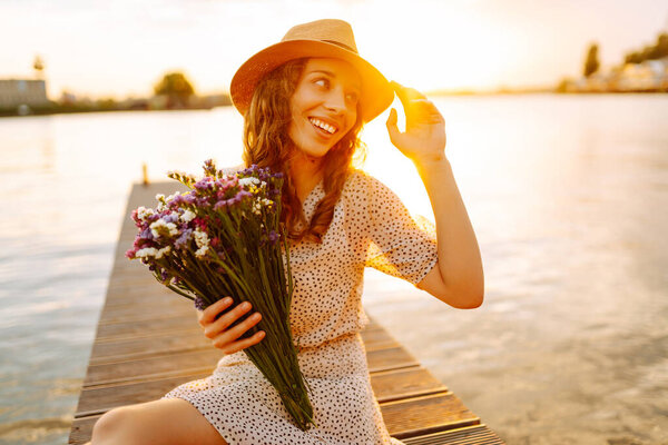 Молодая женщина стояла на мосту, глядя на реку внизу, и крепко сжала букет полевых цветов в руке. Захватывающий вид на окружающий пейзаж.