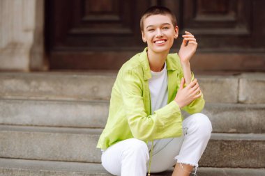 Kısa saçlı mutlu kadın şehir sokaklarında yürüyor. Yaşam tarzı, moda, seyahat kavramı.