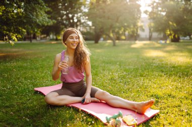 Genç sıska kadın halka açık parkta esneme ya da yoga gevşeme egzersizi yapıyor. Yaşam tarzı ve meditasyon konsepti.