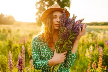 Mor lavanta tarlasında elinde bir buket yabani çiçekle güzel bir kadın. Özgürlük, neşe ve yaşam tarzı kavramı. Şifalı bitkiler..