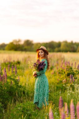 Mor lavanta tarlasında elinde bir buket yabani çiçekle güzel bir kadın. Özgürlük, neşe ve yaşam tarzı kavramı. Şifalı bitkiler..