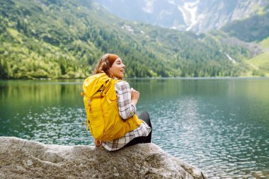 Sırt çantalı genç bir kadın tepenin üstünde dururken güzel doğanın tadını çıkarıyor. Çevre turizmi. Seyahat, macera.