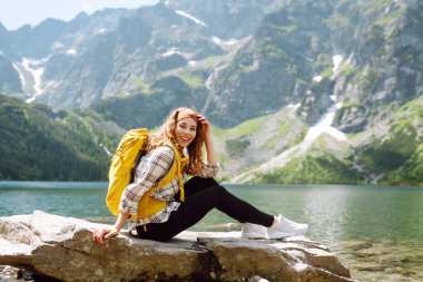 Sırt çantalı genç bir kadın tepenin üstünde dururken güzel doğanın tadını çıkarıyor. Çevre turizmi. Seyahat, macera.