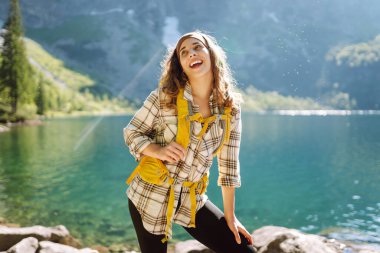 Sırt çantalı genç bir kadın tepenin üstünde dururken güzel doğanın tadını çıkarıyor. Çevre turizmi. Seyahat, macera.
