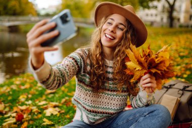 Mutlu Turist havanın tadını çıkarıyor, sarı yapraklı bir fotoğraf çekiyor. Seyahat blogu. Selfie zamanı..