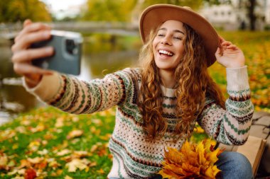 Mutlu Turist havanın tadını çıkarıyor, sarı yapraklı bir fotoğraf çekiyor. Seyahat blogu. Selfie zamanı..