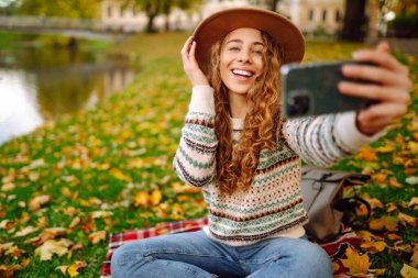 Mutlu Turist havanın tadını çıkarıyor, sarı yapraklı bir fotoğraf çekiyor. Seyahat blogu. Selfie zamanı..
