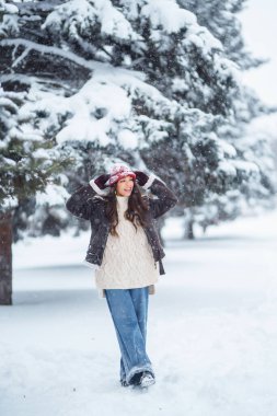 Genç bir kadın kış günü parkta karla eğleniyor. Eğlence, rahatlama, kış tatili kavramı.