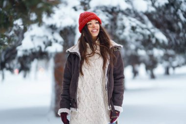 Genç bir kadın kış günü parkta karla eğleniyor. Eğlence, rahatlama, kış tatili kavramı.