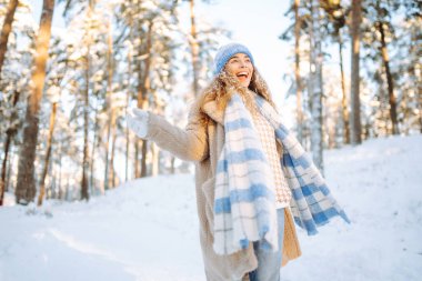 Genç bir kadın eğleniyor, kışın karlı bir parkta yürüyor. İnsanlar, mevsim ve Noel konsepti.