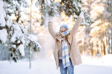 Genç bir kadın eğleniyor, kışın karlı bir parkta yürüyor. İnsanlar, mevsim ve Noel konsepti.