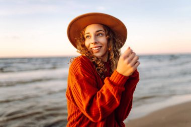 Rüzgarlı bir günde güzel bir kadın kumsal boyunca yürür ve sonbahar havasının tadını çıkarır. Seyahat, hafta sonu, rahatlama ve yaşam tarzı konsepti.