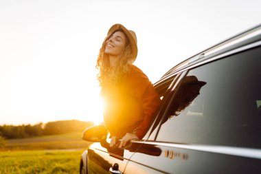 Mutlu kadın arabada günbatımının tadını çıkarıyor. Yaşam tarzı, seyahat, turizm, doğa, aktif yaşam.