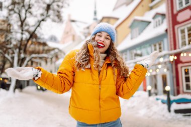 Genç kadın turist, parlak çelenklerle süslenmiş kış caddelerinde yürüyor. Kış tatili Noel Fuarı.