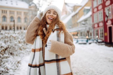 Kıvırcık saçlı kadın karlı bir caddede kış tatilinin tadını çıkarıyor. Kış tatili.