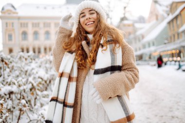 Kıvırcık saçlı kadın karlı bir caddede kış tatilinin tadını çıkarıyor. Kış tatili.